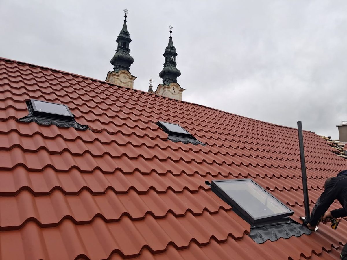 Nová pálená škridlová strecha rodinného domu, v pozadí kostolné veže